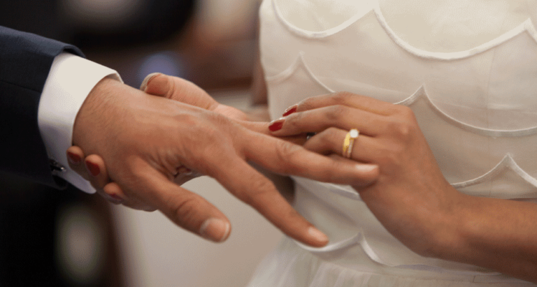 Woman putting wedding band on man's finger